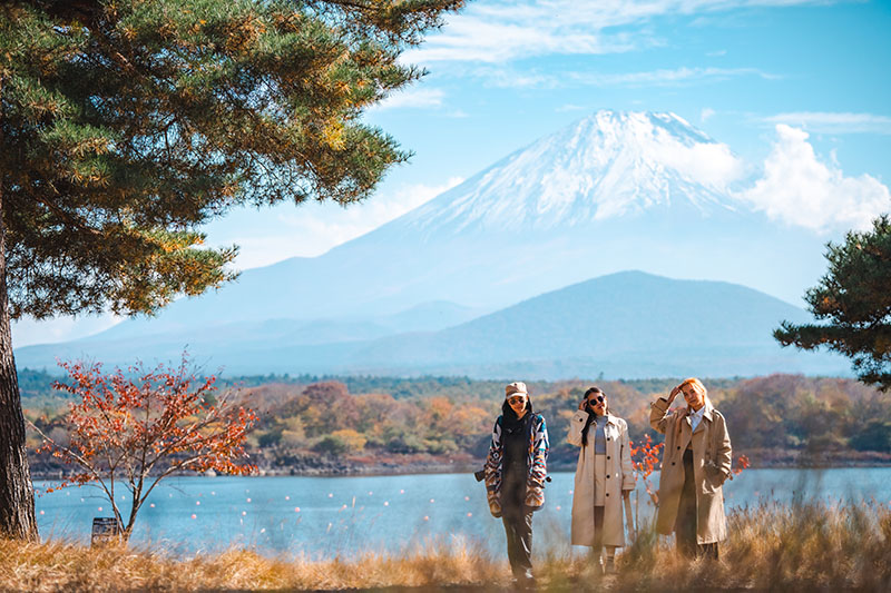 Happy introverted tourist traveler woman or man enjoying on lake kawaguchiko with mount fuji in japan